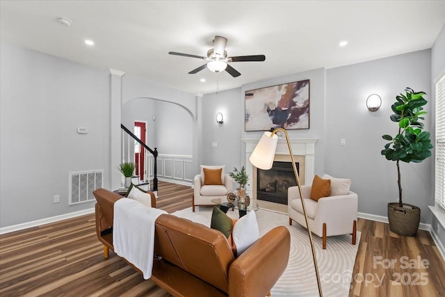 2527 Fossil Stone Ln, Fort Mill, SC 29708 - living area with arched walkways, wood finished floors, ceiling fan, a glass covered fireplace, and stairway