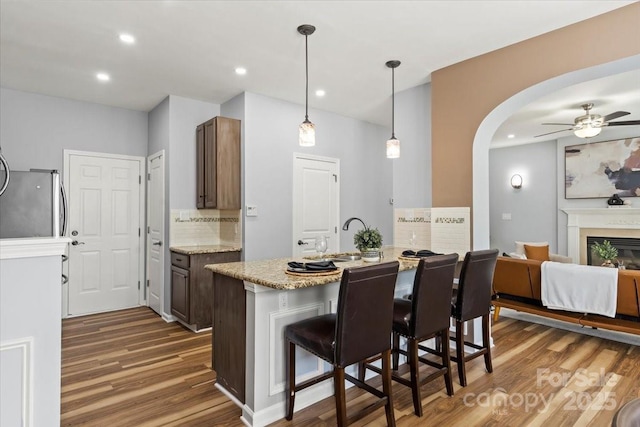 2527 Fossil Stone Ln, Fort Mill, SC 29708 - kitchen with dark wood-type flooring, a ceiling fan, a kitchen breakfast bar, backsplash, and pendant lighting