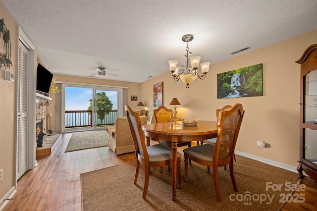 2881 White Oak Mountain Rd Unit D5, Columbus, NC 28722 - dining area with a chandelier, a textured ceiling, wood finished floors, and a stone fireplace
