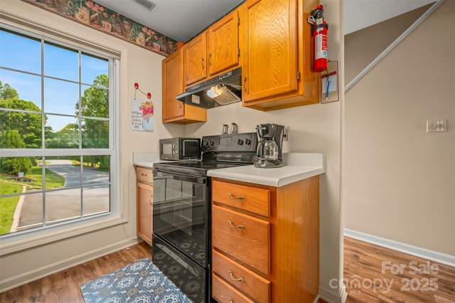 2881 White Oak Mountain Rd Unit D5, Columbus, NC 28722 - kitchen featuring black appliances, under cabinet range hood, light countertops, wood finished floors, and brown cabinetry