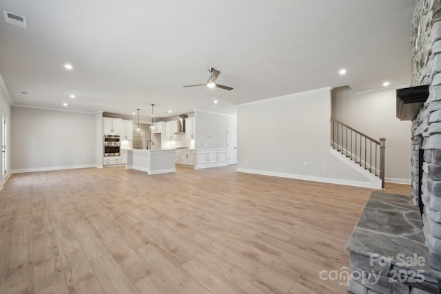 308 Alameda Way, Matthews, NC 28104 - unfurnished living room with a ceiling fan, stairs, a stone fireplace, recessed lighting, and crown molding