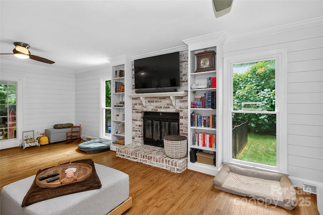8300 Quarters Ln, Mint Hill, NC 28227 - living room featuring a ceiling fan, wood finished floors, a brick fireplace, ornamental molding, and wood walls