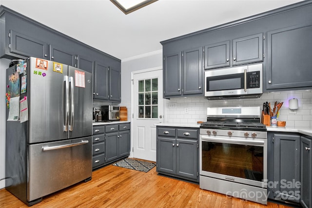8300 Quarters Ln, Mint Hill, NC 28227 - kitchen featuring stainless steel appliances, light countertops, ornamental molding, light wood-style flooring, and backsplash