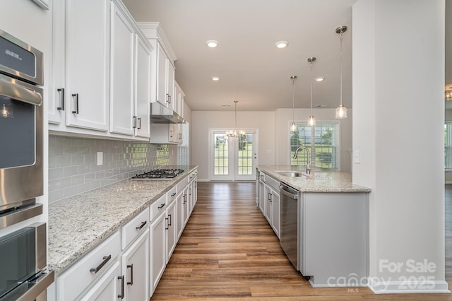 8420 Golden Stone Ln Unit 138, Fort Mill, SC 29707 - kitchen with stainless steel appliances, wood finished floors, white cabinetry, backsplash, and light stone countertops