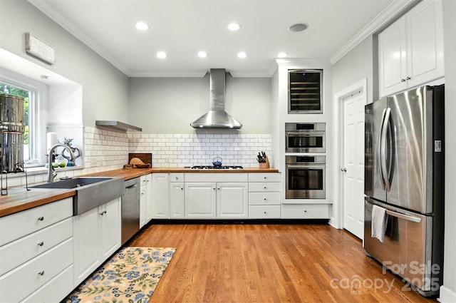 1009 13th Avenue Pl NW Unit 19, Hickory, NC 28601 - kitchen featuring appliances with stainless steel finishes, wooden counters, wall chimney range hood, ornamental molding, and white cabinetry