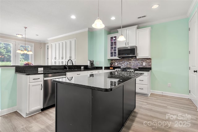 1152 Mckee Farm Ln, Belmont, NC 28012 - kitchen with appliances with stainless steel finishes, a peninsula, ornamental molding, light wood-type flooring, and white cabinets