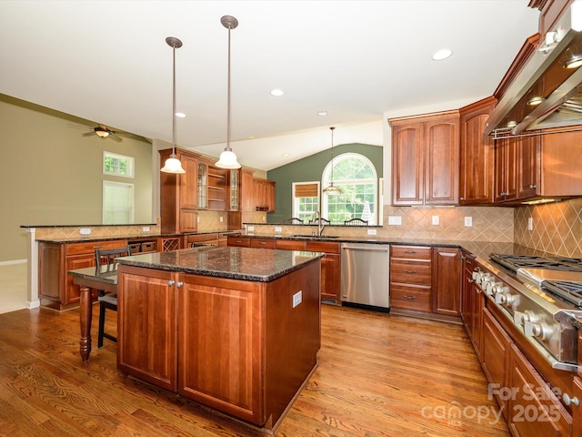 9212 John Hawks Rd, Cornelius, NC 28031 - kitchen featuring stainless steel appliances, wall chimney exhaust hood, a kitchen island, tasteful backsplash, and vaulted ceiling
