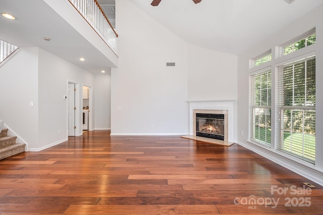 19509 Trintella Ln, Cornelius, NC 28031 - unfurnished living room with high vaulted ceiling, stairs, hardwood / wood-style flooring, a ceiling fan, and a fireplace with flush hearth