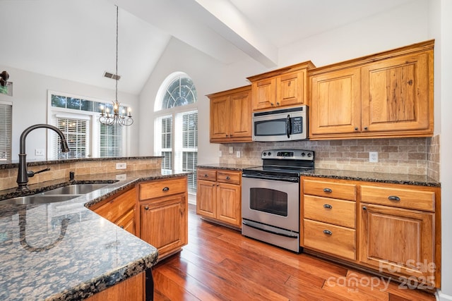 19509 Trintella Ln, Cornelius, NC 28031 - kitchen featuring stainless steel appliances, wood finished floors, lofted ceiling, backsplash, and a chandelier