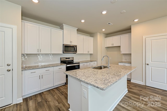 117 Canoga Ave, York, SC 29745 - kitchen featuring appliances with stainless steel finishes, dark wood finished floors, white cabinetry, decorative backsplash, and a center island with sink
