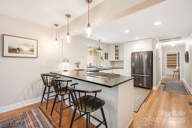 90 Reed Rd, Asheville, NC 28805 - kitchen with stainless steel appliances, dark countertops, a peninsula, glass insert cabinets, and light wood finished floors