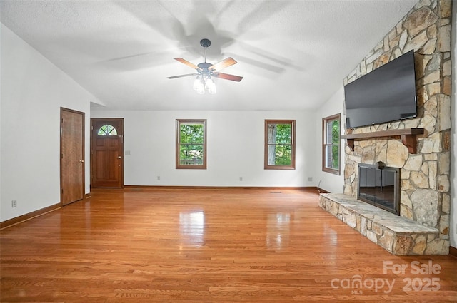 4323 Crow Rd, Monroe, NC 28112 - unfurnished living room with a stone fireplace, wood finished floors, a ceiling fan, lofted ceiling, and a textured ceiling