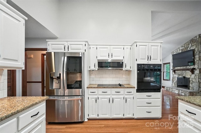 4323 Crow Rd, Monroe, NC 28112 - kitchen with black appliances, a fireplace, light wood-style flooring, backsplash, and light stone countertops