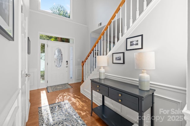 13934 Kings Carriage Ln, Charlotte, NC 28278 - entryway with a towering ceiling, wood finished floors, stairs, a decorative wall, and wainscoting