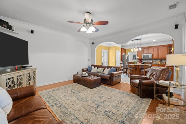 13934 Kings Carriage Ln, Charlotte, NC 28278 - living room with arched walkways, ceiling fan, light wood-style floors, and ornamental molding