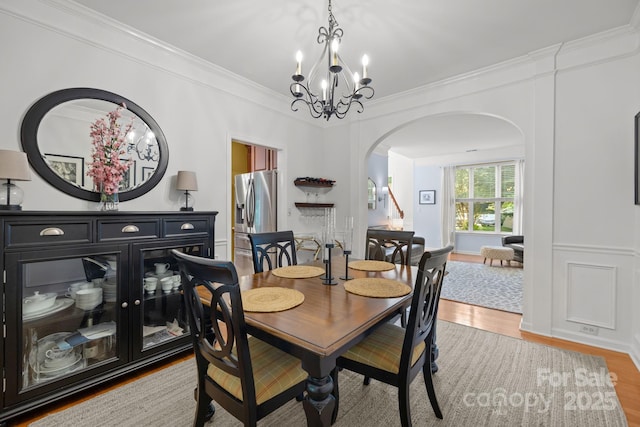 13934 Kings Carriage Ln, Charlotte, NC 28278 - dining area with arched walkways, a chandelier, light wood finished floors, and ornamental molding