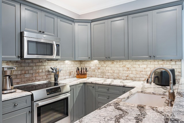 609 Carriage Commons Dr, Hendersonville, NC 28791 - kitchen with appliances with stainless steel finishes, gray cabinetry, light stone countertops, tasteful backsplash, and ornamental molding