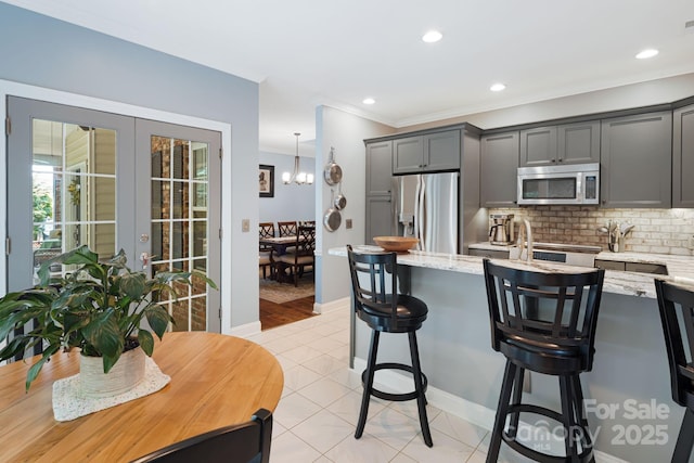 609 Carriage Commons Dr, Hendersonville, NC 28791 - kitchen featuring appliances with stainless steel finishes, french doors, backsplash, a breakfast bar area, and light stone counters