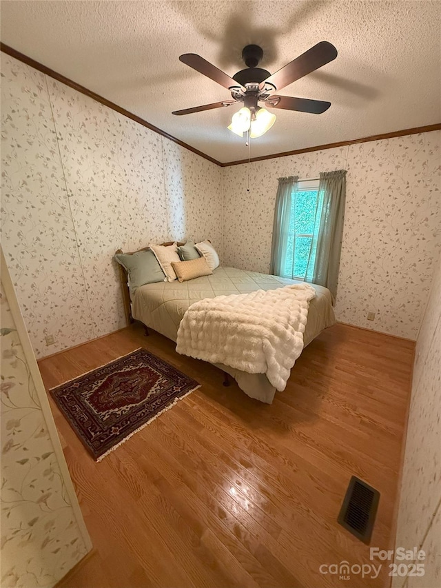 400 Archibald Rd, Concord, NC 28025 - bedroom featuring ornamental molding, wood finished floors, a textured ceiling, wallpapered walls, and a ceiling fan