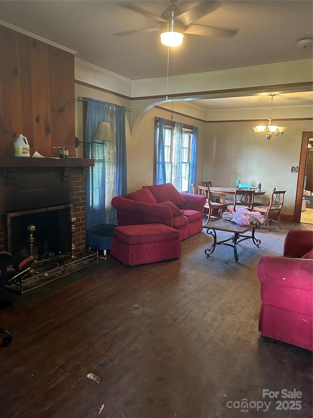 3220 Harmony Hwy, Harmony, NC 28634 - living room featuring ornamental molding, wood-type flooring, a ceiling fan, arched walkways, and a brick fireplace