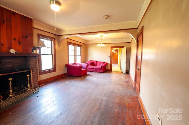 3220 Harmony Hwy, Harmony, NC 28634 - living room featuring ornamental molding, hardwood / wood-style flooring, arched walkways, a brick fireplace, and a chandelier