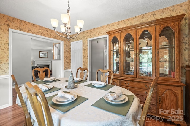 171 Highland Woods Ct, Denver, NC 28037 - dining room with wallpapered walls, a chandelier, wood finished floors, and a fireplace