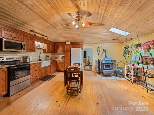 449 Little E Fork Rd, Canton, NC 28716 - kitchen featuring stainless steel appliances, vaulted ceiling, wood ceiling, a wood stove, and brown cabinetry
