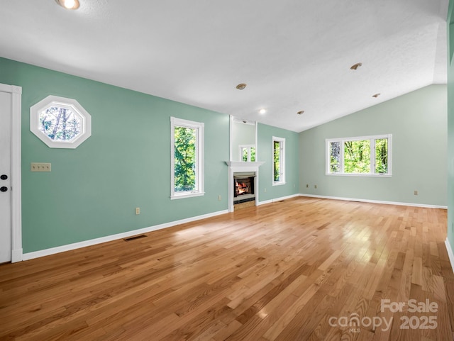 436 Utsonati Ln, Brevard, NC 28712 - unfurnished living room featuring light wood-type flooring, a warm lit fireplace, and lofted ceiling