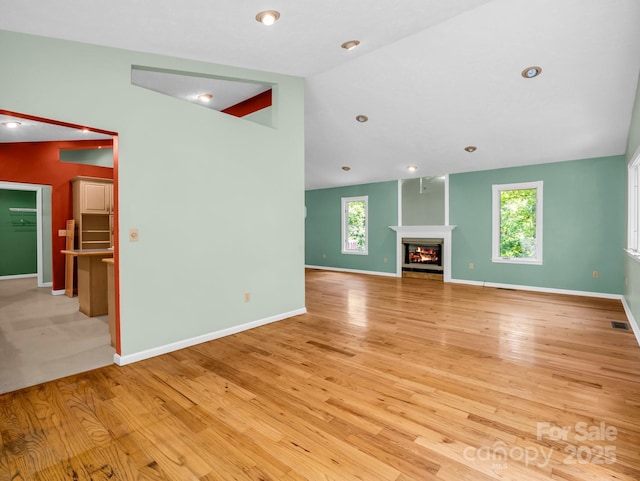 436 Utsonati Ln, Brevard, NC 28712 - unfurnished living room featuring light wood-style flooring, a glass covered fireplace, and vaulted ceiling