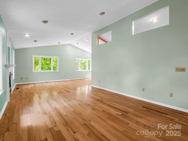 436 Utsonati Ln, Brevard, NC 28712 - unfurnished living room with light wood-style flooring, lofted ceiling, and a glass covered fireplace