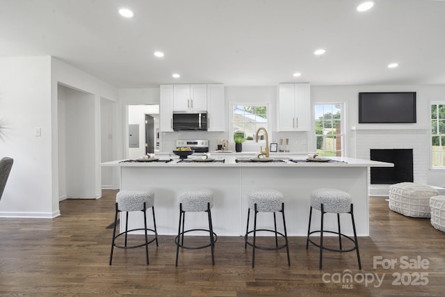 5817 Red Carriage Ln, Charlotte, NC 28212 - kitchen with stainless steel microwave, range, a kitchen bar, white cabinets, and recessed lighting