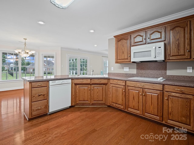2872 Wheat Field Ct, Lincolnton, NC 28092 - kitchen featuring white appliances, wood finished floors, a chandelier, crown molding, and a peninsula