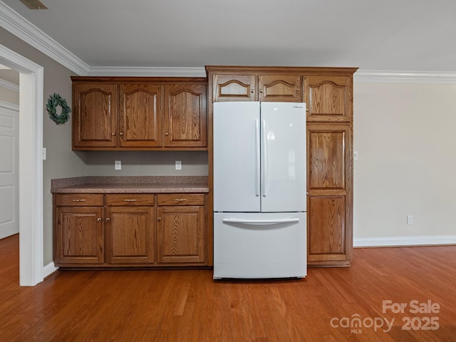 2872 Wheat Field Ct, Lincolnton, NC 28092 - kitchen featuring freestanding refrigerator, crown molding, wood finished floors, and brown cabinets