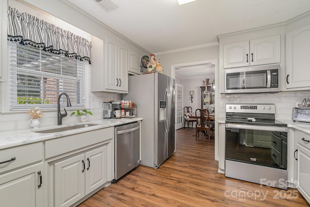 1610 Union Rd Unit 1610B, Gastonia, NC 28054 - kitchen with stainless steel appliances, ornamental molding, light wood-style floors, tasteful backsplash, and white cabinets