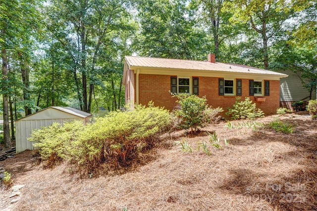 9763 Pine Tree Rd, Norwood, NC 28128 - view of front facade featuring brick siding, an outbuilding, a metal roof, and a chimney