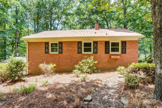 9763 Pine Tree Rd, Norwood, NC 28128 - view of side of home featuring brick siding, a chimney, and a metal roof
