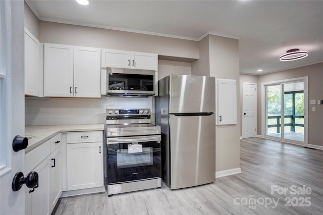9763 Pine Tree Rd, Norwood, NC 28128 - kitchen with stainless steel appliances, backsplash, light wood-style floors, white cabinets, and crown molding