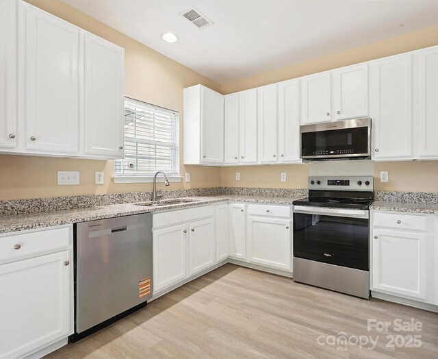 3043 Streamlet Way, Monroe, NC 28110 - kitchen featuring appliances with stainless steel finishes, white cabinetry, light wood-style floors, light stone counters, and recessed lighting
