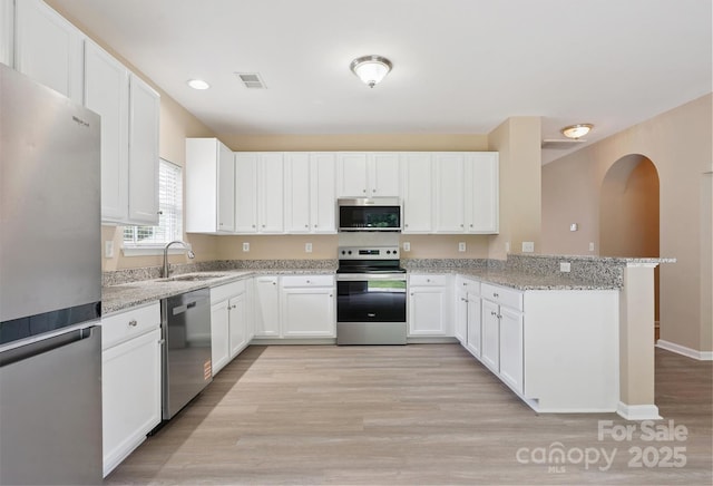 3043 Streamlet Way, Monroe, NC 28110 - kitchen featuring stainless steel appliances, a peninsula, light stone countertops, and white cabinetry