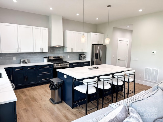 154 Amblers Knoll Rd, Weaverville, NC 28787 - kitchen with stainless steel appliances, wall chimney exhaust hood, a kitchen bar, tasteful backsplash, and light wood finished floors