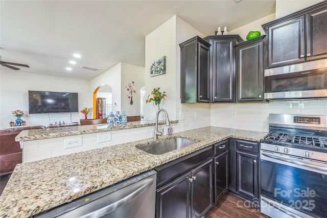 1012 Leland Dr, Wesley Chapel, NC 28104 - kitchen with appliances with stainless steel finishes, arched walkways, open floor plan, dark wood finished floors, and light stone countertops