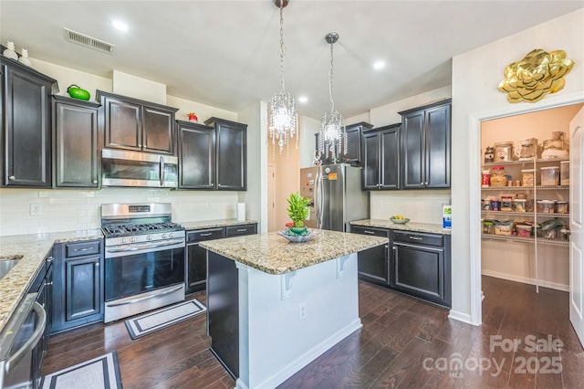 1012 Leland Dr, Wesley Chapel, NC 28104 - kitchen with stainless steel appliances, dark wood-style flooring, light stone countertops, a kitchen island, and recessed lighting