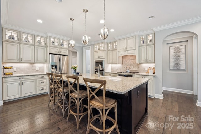 11412 Preservation Ln, Charlotte, NC 28278 - kitchen with arched walkways, stainless steel appliances, backsplash, a kitchen island with sink, and ornamental molding