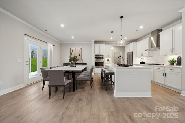 416 Balboa St, Matthews, NC 28104 - kitchen featuring wall chimney range hood, stainless steel appliances, crown molding, a kitchen island with sink, and recessed lighting
