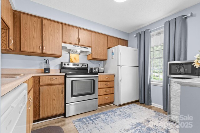 9606 Vinca Cir Unit E, Charlotte, NC 28213 - kitchen featuring stainless steel appliances, under cabinet range hood, light wood finished floors, light countertops, and brown cabinetry
