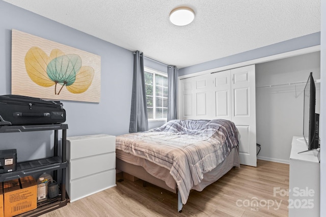 9606 Vinca Cir Unit E, Charlotte, NC 28213 - bedroom with light wood-style flooring, a closet, and a textured ceiling