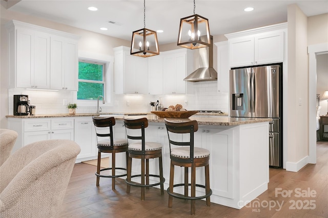 321 Middle Connestee Trl, Brevard, NC 28712 - kitchen featuring stainless steel fridge with ice dispenser, wall chimney exhaust hood, a center island, white cabinets, and a kitchen breakfast bar