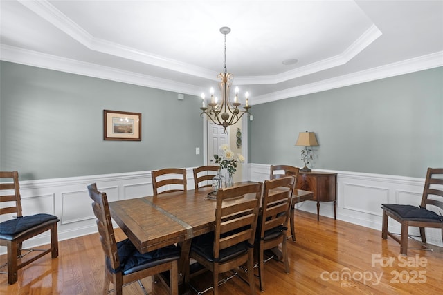 1119 Williamstown Rd, Matthews, NC 28105 - dining area featuring light wood-type flooring, a chandelier, crown molding, wainscoting, and a decorative wall
