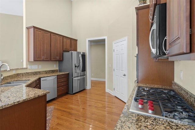 1119 Williamstown Rd, Matthews, NC 28105 - kitchen with appliances with stainless steel finishes, a high ceiling, light wood-style flooring, light stone countertops, and a peninsula