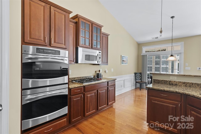 1119 Williamstown Rd, Matthews, NC 28105 - kitchen featuring stainless steel appliances, vaulted ceiling, decorative light fixtures, glass insert cabinets, and light stone countertops